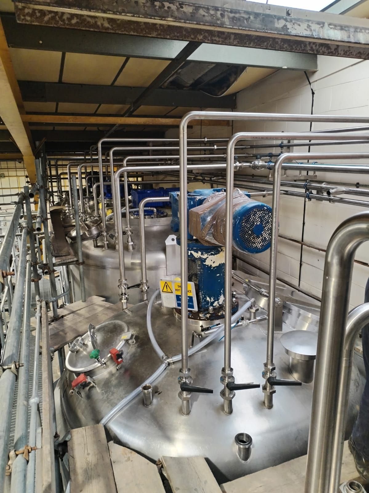 Stainless steel pipework running over a row of stainless tanks