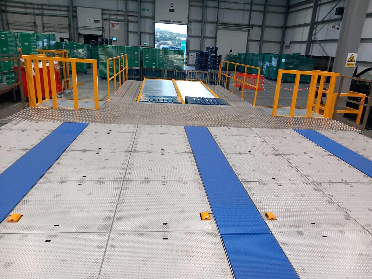 Blue floor tracks and roller beds laid out across a warehouse floor